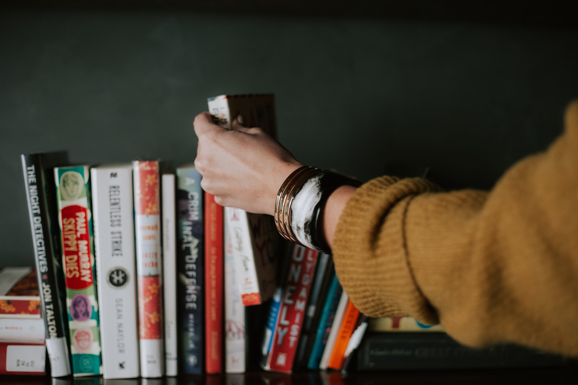 person taking a book from shelf